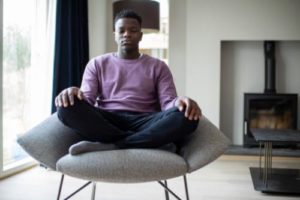 male teen sitting in chair and practicing mindfulness meditation therapy