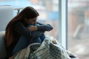 teen girl sitting alone and isolating herself can be a sign of depression in teens