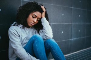 young woman upset sitting on the ground trying to process her childhood trauma