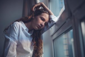 teen girl leaning on the window and distraught after learning teen depression statistics