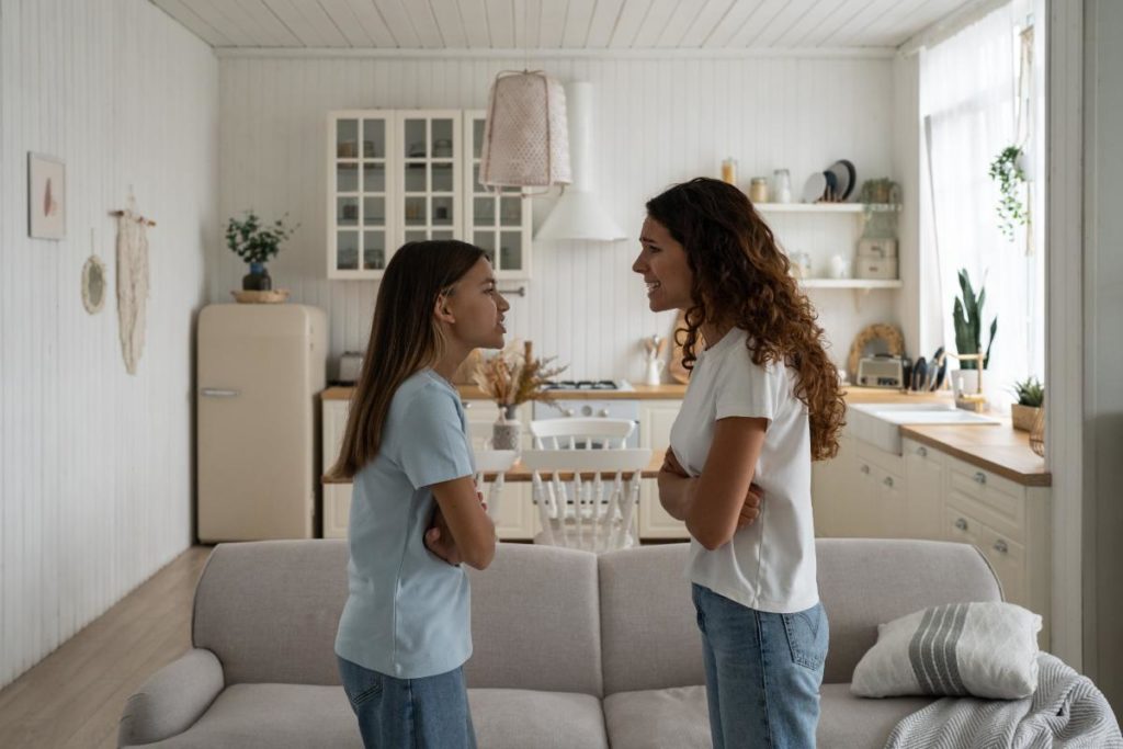 a mother and daughter are facing each other with their arms crossed arguing as the mom is witnessing an angry outburst in her child