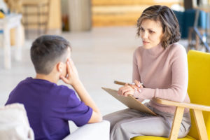 therapist sits with a teen boy to discuss mental health disorders in teens