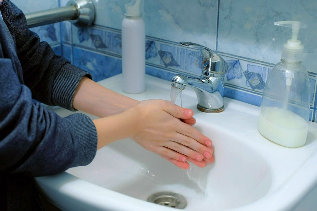 a person washes their hands under a bathroom sink faucet multiple times in a row showing signs of ocd in children