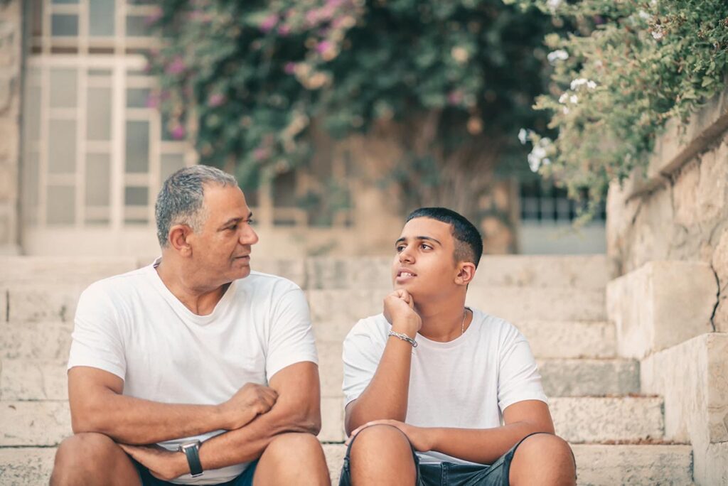 father and son sit on steps outside and son asks is anxiety hereditary
