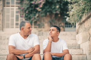 father and son sit on steps outside and son asks is anxiety hereditary