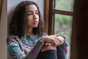 Teen sits on windowsill as they consider the different types of depression