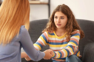 Therapist holds hands with teen who has trouble controlling impulses