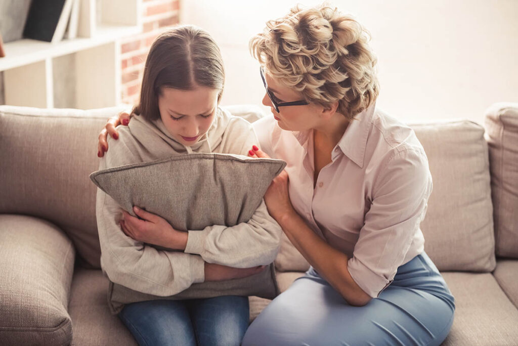 Woman comforts upset teen after learning how to help someone with depression