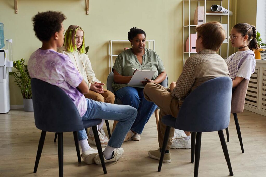 group of young men and women seated in a circle realizing the benefits of group therapy for mental health treatment