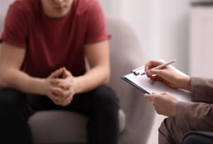 adolescent male talking earnestly with mental health professional about the benefits of partial hospitalization programs for teens.