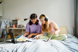 Two teenagers listening to music and looking at magazines while managing school stress.