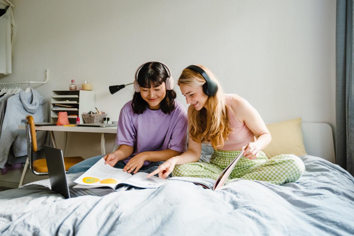 Two teenagers listening to music and looking at magazines while managing school stress.