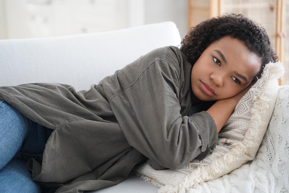 teenage girl look depressed and laying in her bed wondering, "Can depression make you physically ill?"