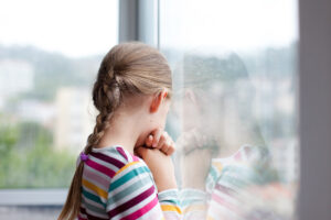 Girl looking out rainy window