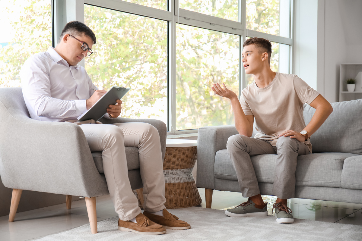 Young man speaking to psychiatrist on couch